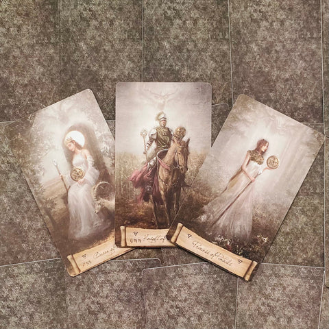 tarot kortos su trimis Pentaklių figūromis — riteris ant žirgo centre, sėdinčios ir stovinčios moterys šonuose, sepijos tonai