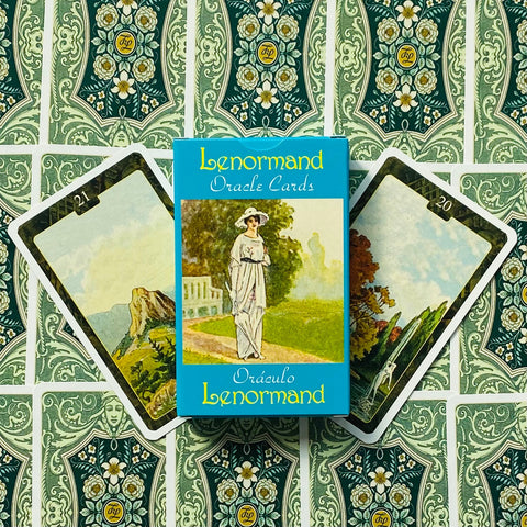 Lenormand kortų kaladė mėlyname dėkle, priekyje matomos dvi atverstos kortos ir raštuotos nugarėlės fone