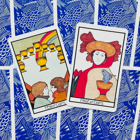 Tarot kortos Rider–Waite stiliaus: dvi priekinės kortos (Ten of Cups ir Page of Cups) ant mėlynos raštuotos nugarėlės, plokščias išdėstymas