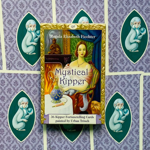 Kipper kortos Mystical Kipper – 36 iliustruotų būrimo kortų dėžutė su aukso rėmu, violetiniu ornamentu ir beždžionių nugarėlėmis