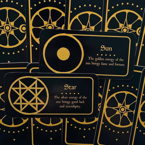 orakulų kortos juodos su auksiniais simboliais, artimas kadras atidengia „Sun“ ir „Star“ kortų aiškinimus