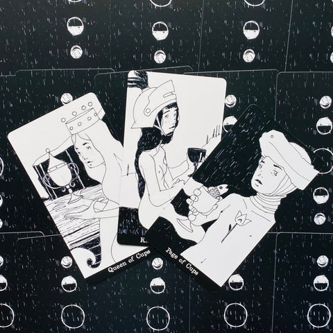 tarot kortos juodai baltos iliustracijos, trys išskleistos Taurių rūšies kortos (Queen ir Page of Cups) ant juodo nugarėlių rašto