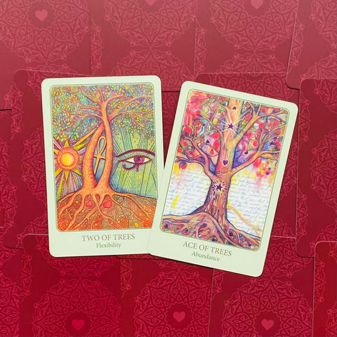 Tarot kortos – dvi spalvingos kortos Two of Trees (Lankstumas) ir Ace of Trees (Gausa) ant raudonų ornamentuotų nugarėlių.