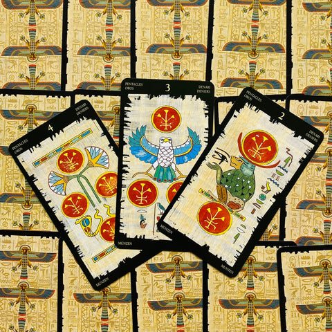 tarot kortos egiptų dizaino nugarėmis, trys atverstos Pentaklių kortos su raudonais ženklais
