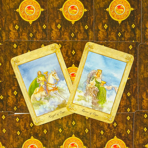 tarot kortos su akvarelinėmis Riterio ir Karalienės taurėse iliustracijomis, aukso rėmeliai ir matoma kortų priekinė pusė