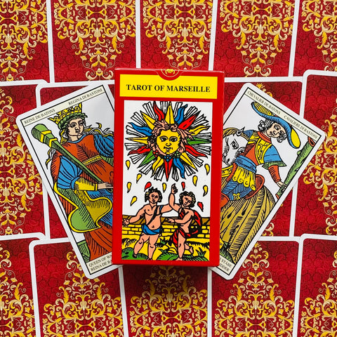 Tarot kortos Marseille komplektas, raudona dėžutė centre ir dvi atvertos kortos ant ornamentinio raudono fono