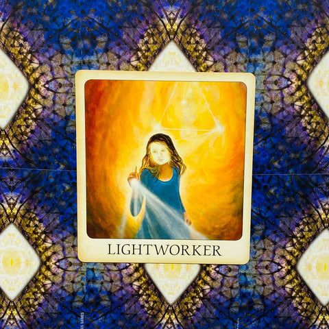 Lightworker korta su mėlyna figurele ir intensyviu geltonai oranžiniu šviesos fonu, padėta ant raštuoto mėlyno fono