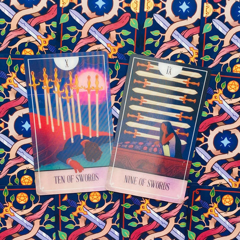 tarot kortos dviejų kortų išklotinė: Ten of Swords ir Nine of Swords atvertos ant mėlyno ornamentuoto fono