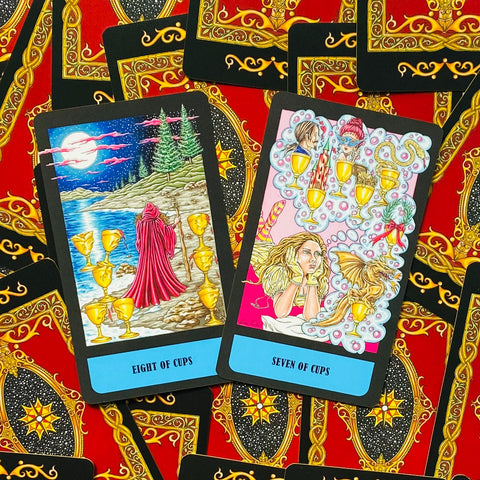 Tarot kortos su iliustracijomis — aštuonių ir septynių taurų kortos su ryškiu mėlynu kraštu ir raudona ornamentine nugarėle