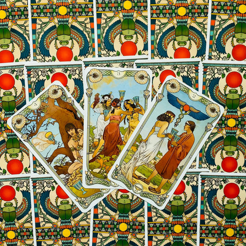 Tarot kortos su ryškiais egiptietiško rašto nugarėmis, trys atverstos taurių kortos fanu, detali vintage iliustracija ir sodrios spalvos