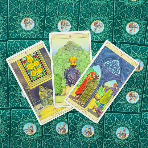 tarot kortos su žaliais ornamentuotais nugarėliais, nuotraukoje trys atviros Pentaklių kortos iš viršaus — variantas su pavyzdine išdėstymo kompozicija