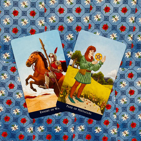 tarot kortos Rider–Waite stiliaus — dvi kortos (Riteris lazdoms ir Pentaklių puslapis) ant mėlyno gėlių fono, rodo dizaino ir spalvų variantą