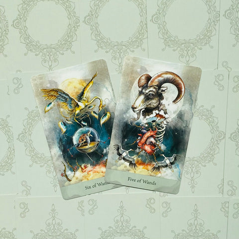 tarot kortos – dvi priekinės kortos (Six of Wands ir Five of Wands) su detaliais, spalvingais simboliniais piešiniais ir mėlyvai pilku fonu