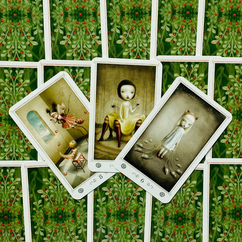 Tarot kortos — trijų kortų atversta kompozicija: centrinė figūra geltonoje suknelėje ant žalių uogotų nugarėlių