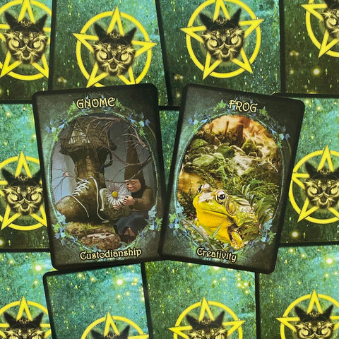 Orakulo kortos dvigubas atidarymas: centre Gnome (Custodianship) ir Frog (Creativity) ant žalsvo žvaigždėto nugarėlių fono