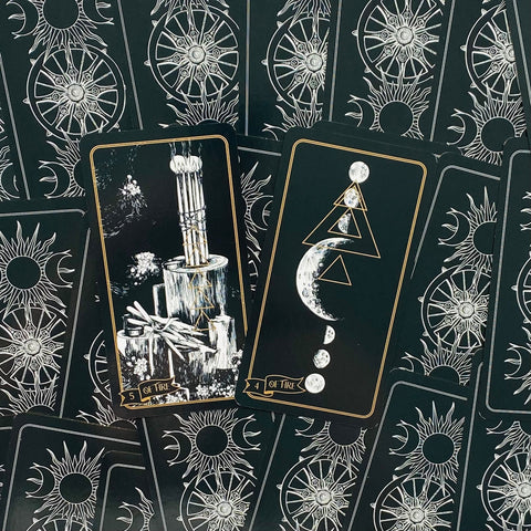 Tarot kortos juodos su auksiniu kraštu, dvi atviros kortos centre su mėnulio ir žvakių motyvais, skirtos skaitymui ir dovanai