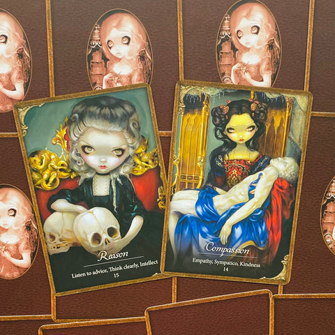 tarot kortos su mistinėmis iliustracijomis — „Reason“ su kaukole ir „Compassion“ nešanti kūną, geltoni ir mėlyni akcentai