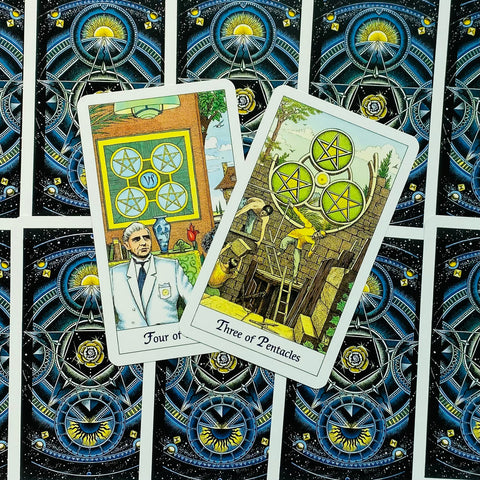 Tarot kortos Rider–Waite komplektas su atviromis Keturių ir Trijų pentaklų kortomis ant mėlynos–juodos kosminės nugarėlės