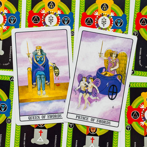 Tarot kortos Queen of Swords ir Prince of Swords, dvi priekinės kortos ant spalvingų nugarėlių — ryškūs simboliai ir violetinė fono gama