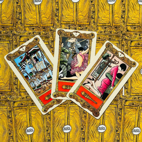 Tarot kortos Guido Crepax: trys spalvingos iliustruotos kortos atverstos fanuota išdėstytos ant aukso rašto fono