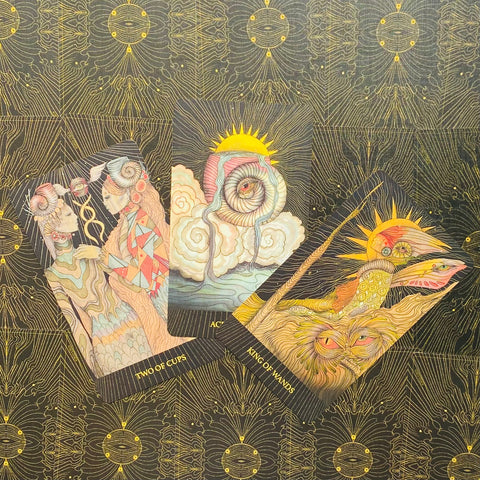 tarot kortos su pastelinėmis siurrealistinėmis iliustracijomis — trys atverstos kortos fane ant juodo, auksiniu ornamentuoto fono, skirtos pirkimui
