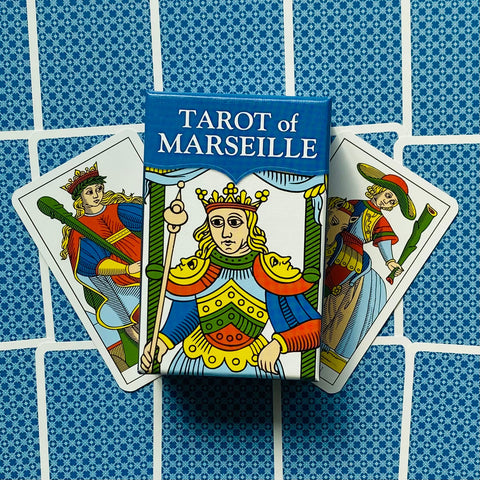 Tarot kortos Marseille komplektas su mėlyna dėžute ir trimis atverstomis kortomis, fanuotos iš priekio