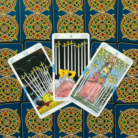 Tarot kortos Rider–Waite stiliaus, trys kortos (8, 9, 10 kalavijų) išdėstytos ant mėlynos ornamentuotos nugarėlės, rodoma komplekto variacija