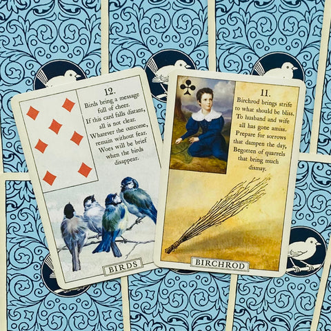 Lenormand kortos: dvi atviros kortos – Birds su keturiais mėlynais paukščiais ir Birchrod su šluotos vaizdu ant mėlyno raštuoto fono