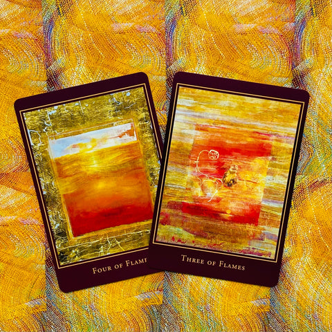 Tarot kortos su aukso ir oranžiniais atspalviais, parodytos dvi kortos (Three of Flames ir Four of Flames) plokščiai išdėstytos