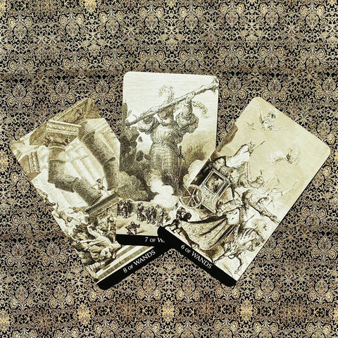 Tarot kortos Wands rinkinys sepijos atspalvio, trys atverstos kortos (6, 7, 8) išdėstytos ant auksuoto rašto audinio