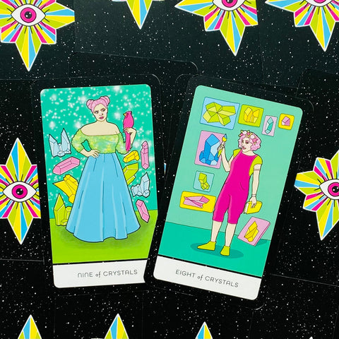 tarot kortos su ryškiomis žalsvomis ir rožinėmis iliustracijomis, matomi „Nine of Crystals“ ir „Eight of Crystals“ ant žvaigždėto juodo fono