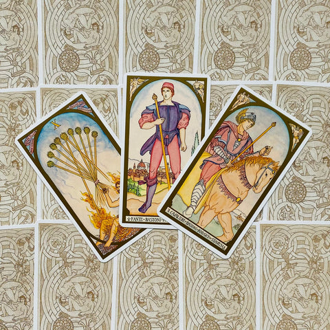 Tarot kortos su spalvotomis Lazdų ir Riterio kortomis, trys variantai išdėstyti fanuotai ant raštuoto nugarėlių fono