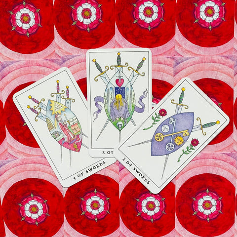 tarot kortos komplektas: trys kalavijų kortos su rankų pieštomis iliustracijomis ant ryškaus raudono žiedų fono, fotografuota iš viršaus