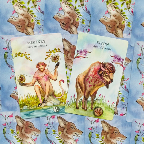 Tarot kortos akvarelinėmis iliustracijomis, dvi atviros kortos Monkey ir Bison ant mėlyno vilko raštuoto fono