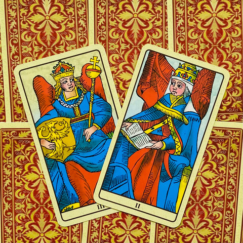 Tarot kortos su dviem atverstomis didžiosiomis kortomis mėlynuose ir raudonuose tonų rūbuose, ant raudono–auksinio nugarėlių rašto