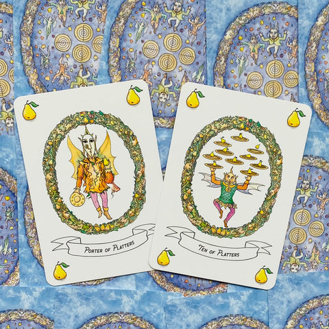 Tarot kortos, dvi iliustruotos kortos (Porter of Platters ir Ten of Platters) ant mėlyno raštuoto fono, pynės vainikai ir kriaušių ikonėlės
