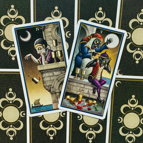 Tarot kortos, dvi atverstos taurų kortos su tamsiai auksine nugarėle ir detaliomis gotikinėmis iliustracijomis