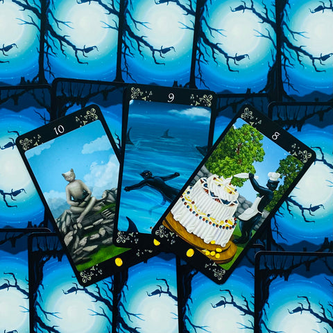 tarot kortos su mėlyna mėnulio nugarėle, trys išskleistos kortos: katės statula ant akmenų, plaukikas jūroje ir virėjo su tortu scena