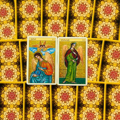 Tarot kortos su geltonu gėlių raštu, dvi atviros kortos centre (Jeliel ir Vehuiah) su ryškiomis iliustracijomis