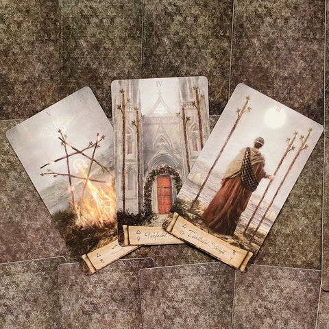 tarot kortos trijų kortų išklotinė su švelniomis pastelinėmis iliustracijomis ir ryškia raudona durų detale, fotografuota iš viršaus priekinio kampo