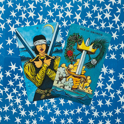 Tarot kortos, dviejų kardų variantas: Ace of Swords ir Two of Swords ant mėlyno žvaigždėto fono, kampu uždėtos