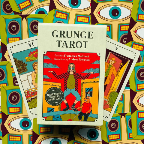 Grunge tarot kortų rinkinys baltame dėkle su raudonu viršeliu ir dviem išskleistomis kortomis ant dekoratyvaus fono