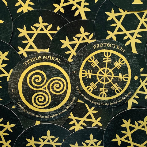 Orakulų kortos juodai–auksinė versija, artimas kampas atskleidžia dvi apvalias korteles su "Triple Spiral" ir "Protection" simboliais.