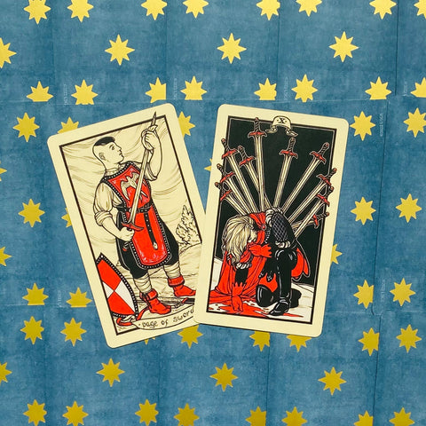 Tarot kortos Rider‑Waite stiliaus: dvi kortos — Page of Swords ir Ten of Swords ant mėlyno žvaigždėto fono, fotografuota iš viršaus