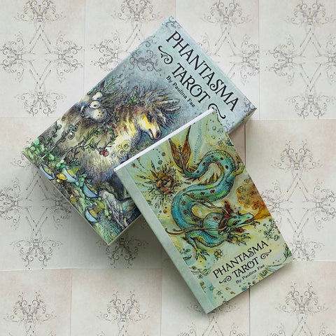 Tarot kortos Phantasma su iliustruota dėžute ir pridedamu vadovu, parodyti du skirtingi dėžių dizainai kampu