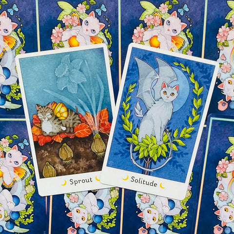 Tarot kortos katėmis, dvi iliustruotos kortos mėlynu fonu (Sprout ir Solitude) ant raštuotos nugarėlės