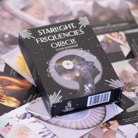 Orakulų kortos Starlight Frequencies juodoje dėžutėje, padėtos ant išskleistų kortų fono, rodydamos pakuotės dizainą