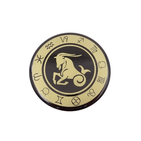 Produktų puslapyje: juoda ir auksinė apvali sagė su Ožiaragio zodiako simboliu, priekinis vaizdas, mažesnis variantas