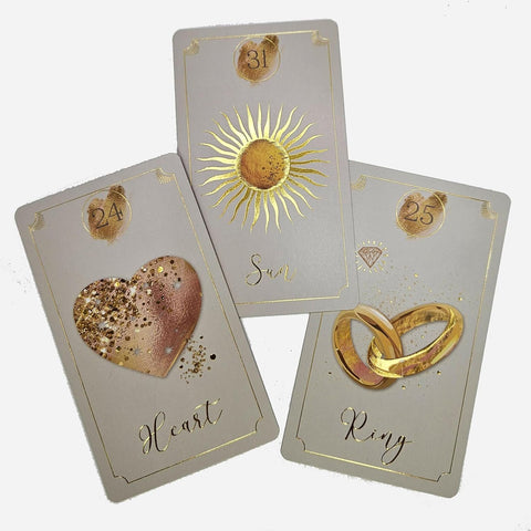 Tarot kortos su pilku fonu ir auksine folija — trys kortos (Sun, Heart, Ring), arti fotografuotos ir persidengiančios