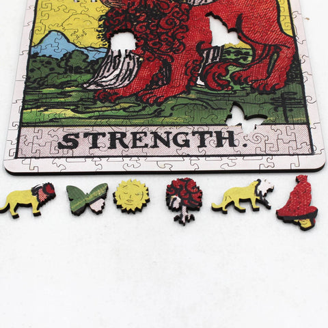 Galvosūkis – medinės formelės (liūtas, drugelis, saulė, medis ir kt.) prie „Strength“ kortelės krašto, ryškios raudonos ir geltonos detalės